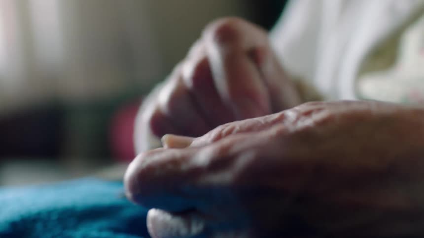 An elderly person tears something with their hands