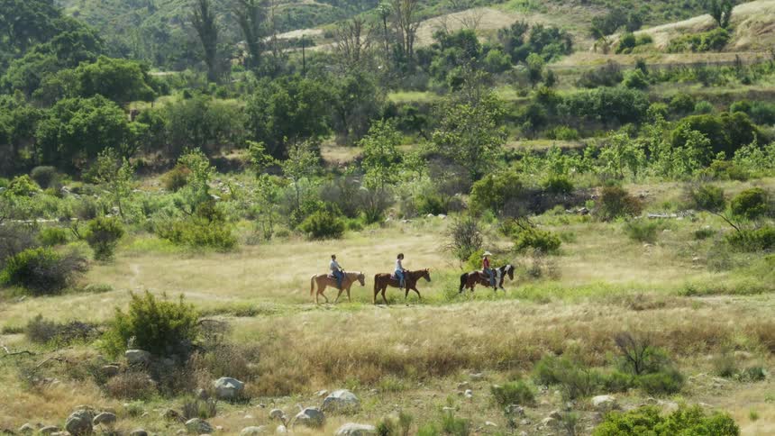 Three people riding horseback in the mountains