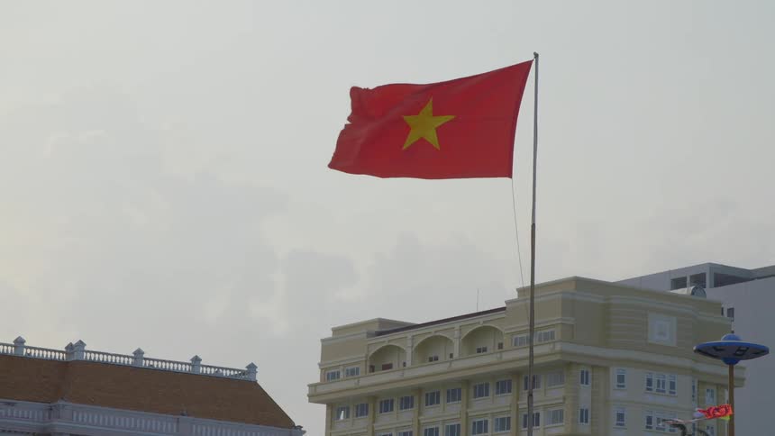 Red flag with a star flies in the breeze in the city