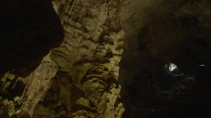Underground footage of the tall ceiling of a cave with a small opening to the outside