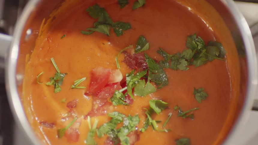 A person is garnishing a soup