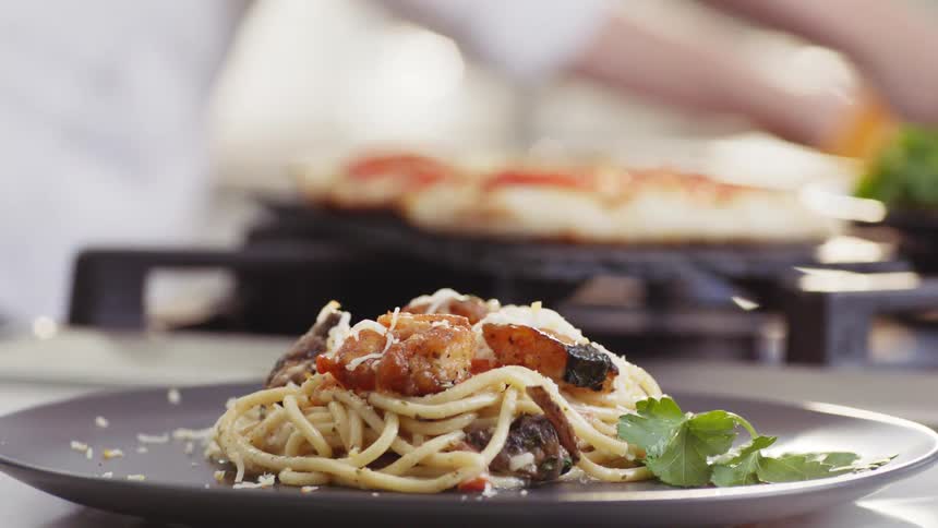 A chef puts the finishing touches on a plate of pasta