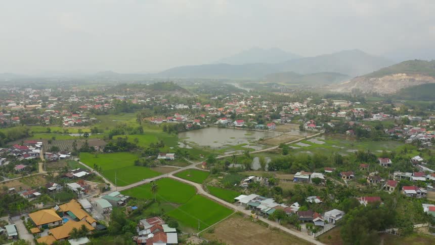 Aerial view of a small town near the hills and mountains covered in fog