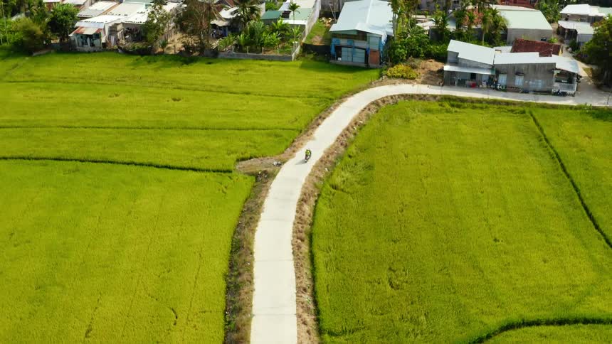 Motorcycle drives to town on a road through the fields