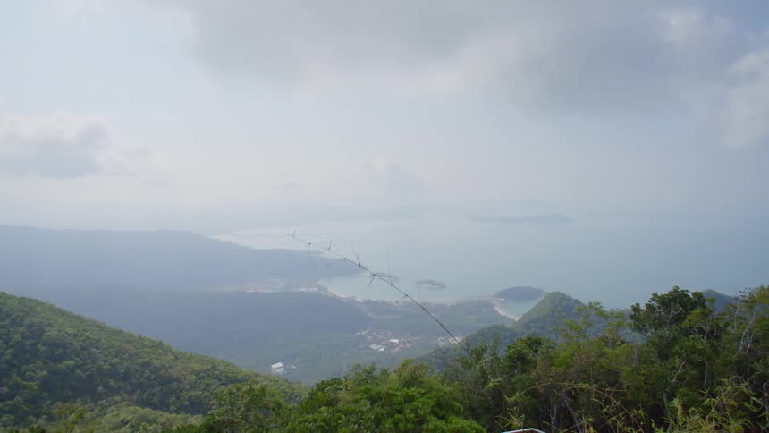 Fog obscures town near shore and islands in ocean under overcast sky