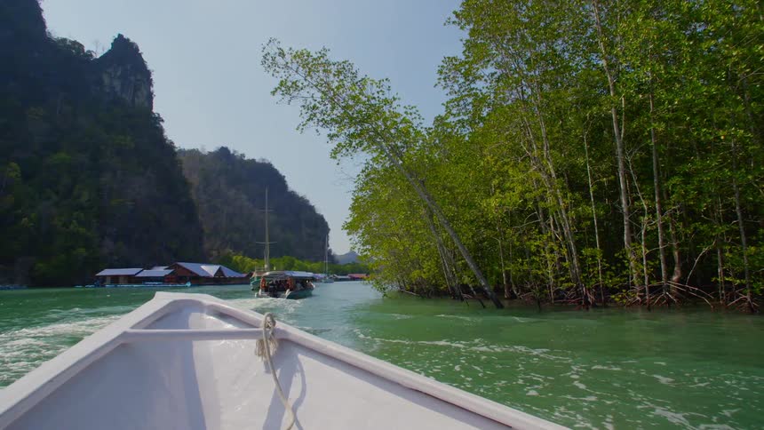 A boat in a river with trees cliffs buildings and the sky in the background