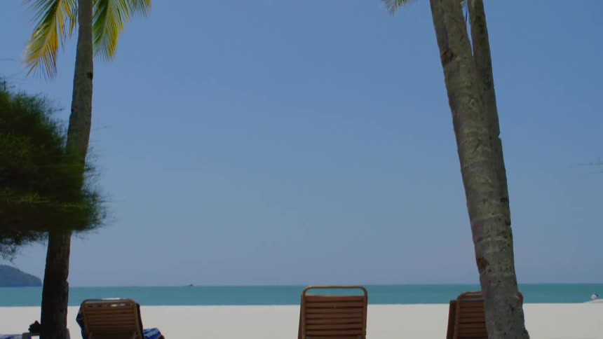 Lounge chairs on a sandy tropical beach in the daytime