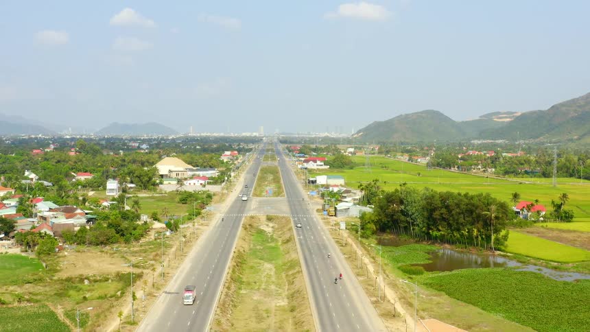 Traffic moves a long a freeway through suburb on a sunny day