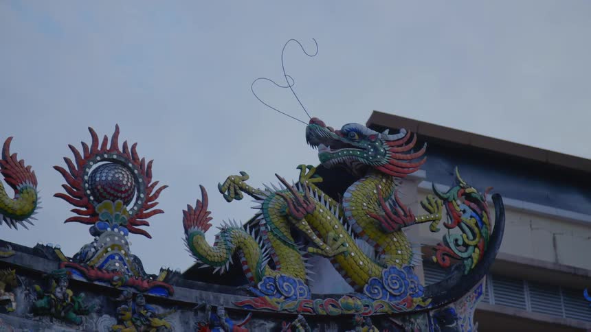 Colorful sculpture of a chinese dragon over an arch in the city