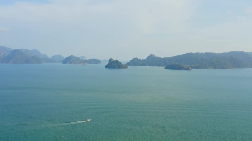 An aerial view of a boat sailing on ocean waters near islands
