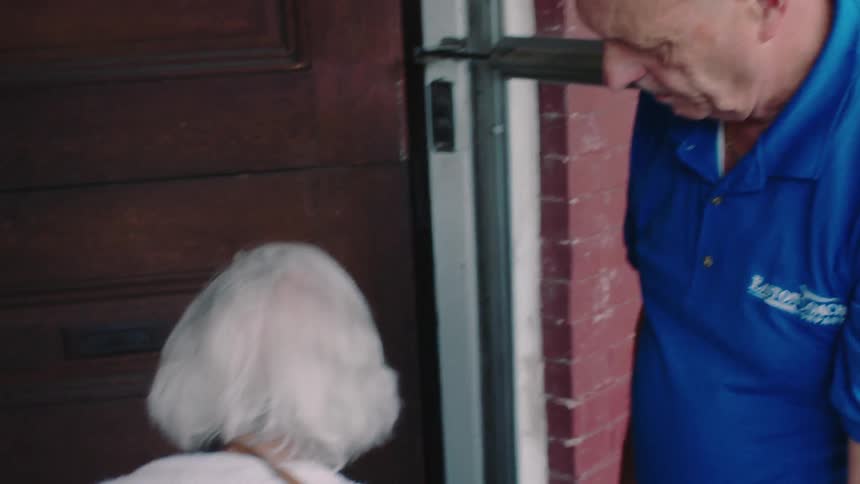 A man holds a door open for a woman walking through