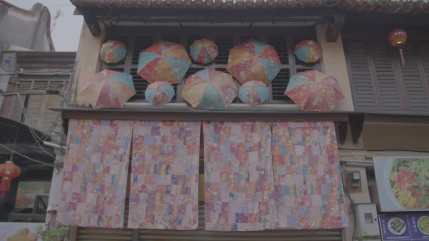 The facade of a building decorated with colorful curtains and umbrellas