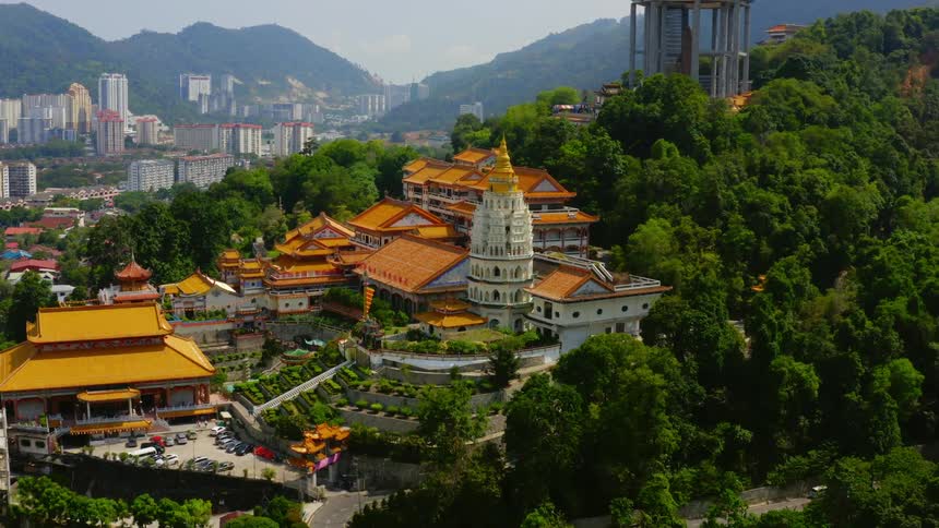 An aerial view of a city next to a forest is displayed