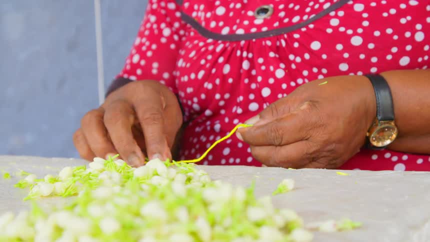 Person sitting at table wraps plant parts with yellow cord