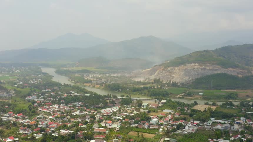 An aerial view of houses in a neighborhood with a river and mountains in the distance