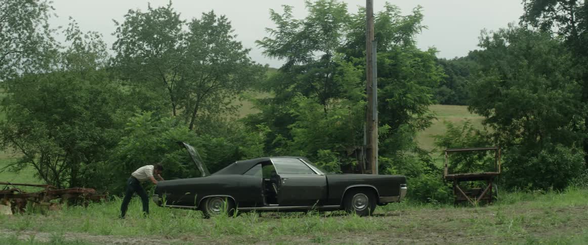 A man is looking at his vehicle in a rural area