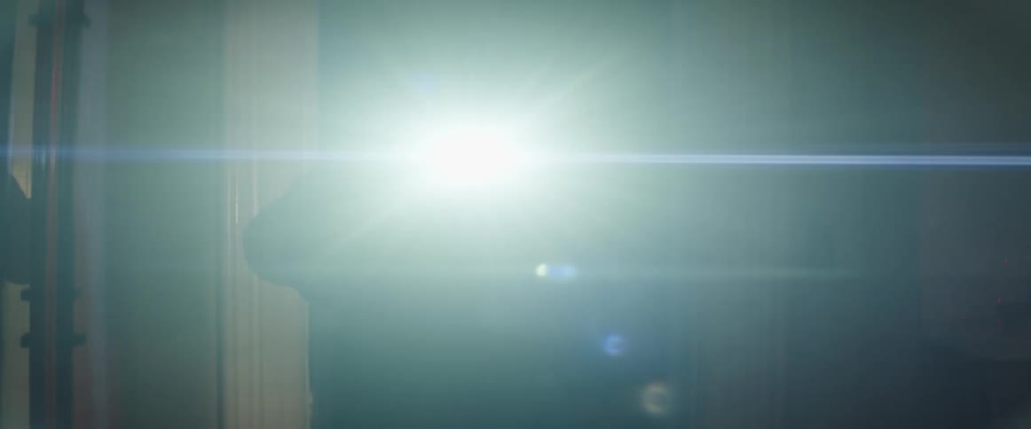 Man carries lit flashlight and baseball while looking through dark house stopping to stare after entering room