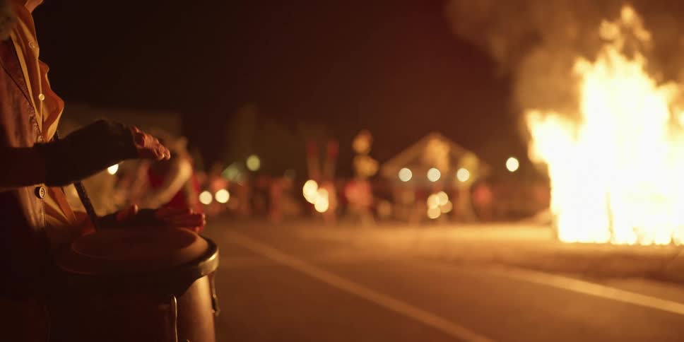 Drummer plays across street from roaring bonfire