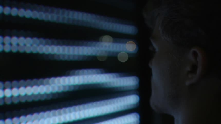 A man is standing close to a large screen