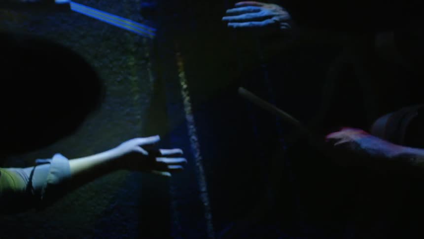 A group of people bang hands and drumsticks on the ground