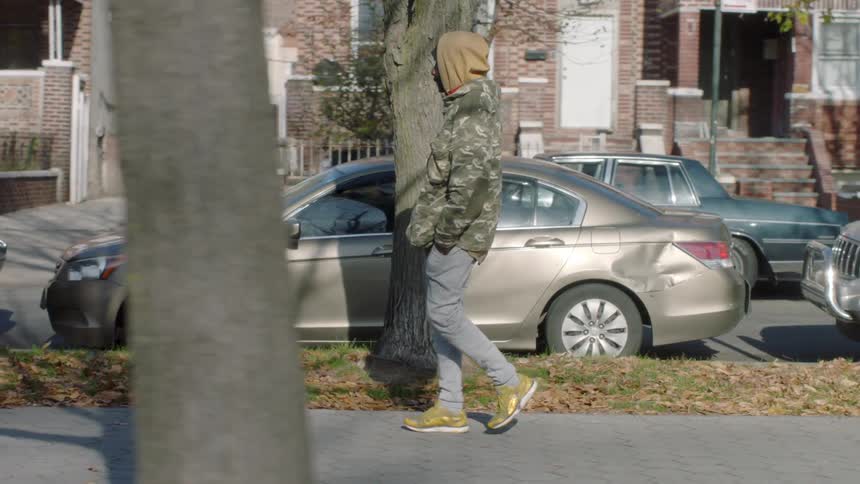 A man in a hoodie walks down the sidewalk