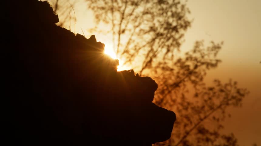 Looking at the sun setting above rocks