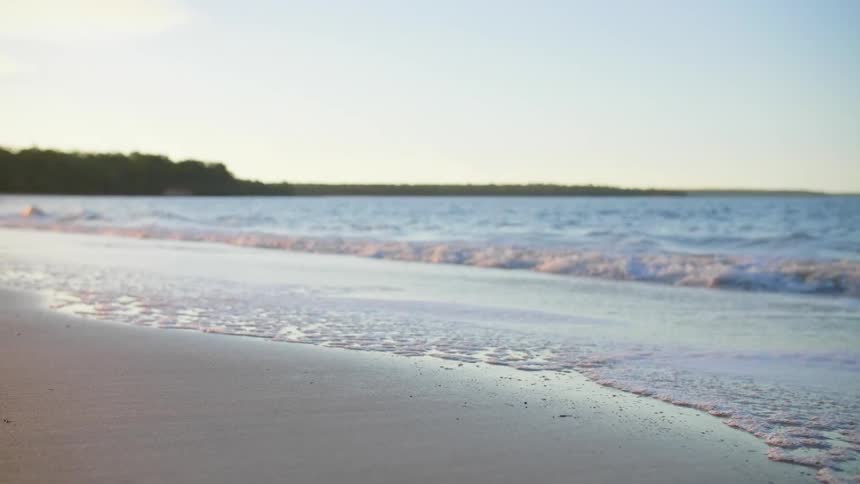 Gentle waves crash onto the shore of a beach