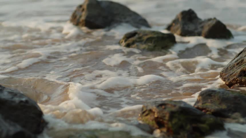 A beach with sand rocks and waves