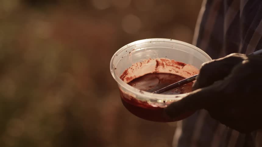 A man holds a small container of paint