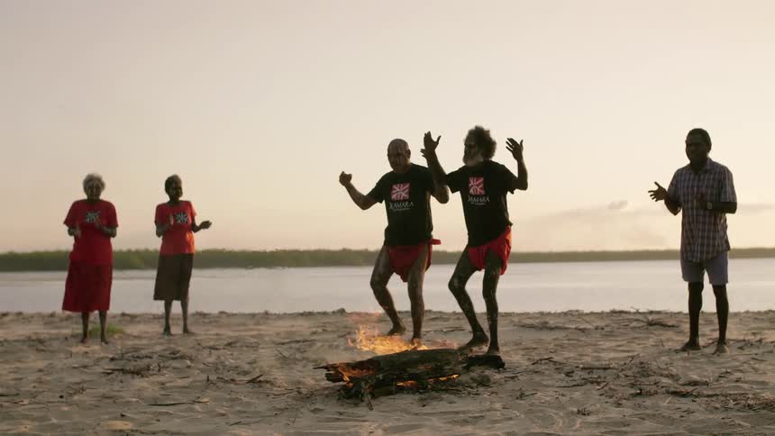 People are dancing and celebrating by a fire