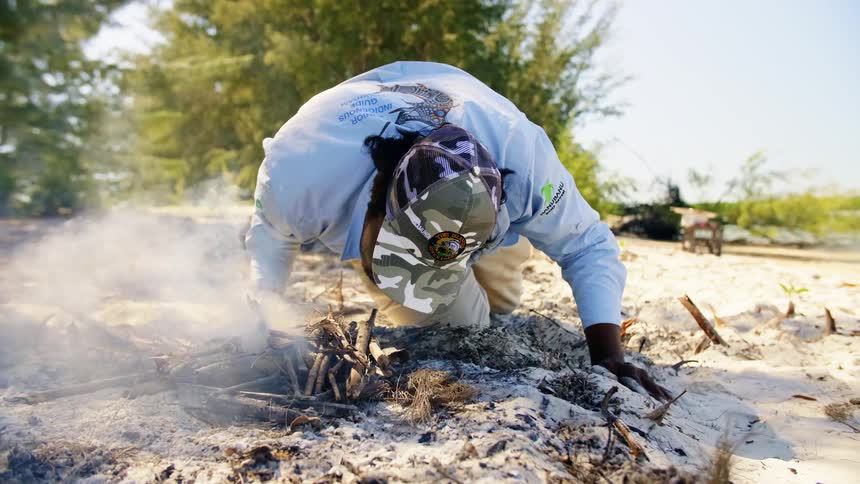 A man blowing on a fire to start it