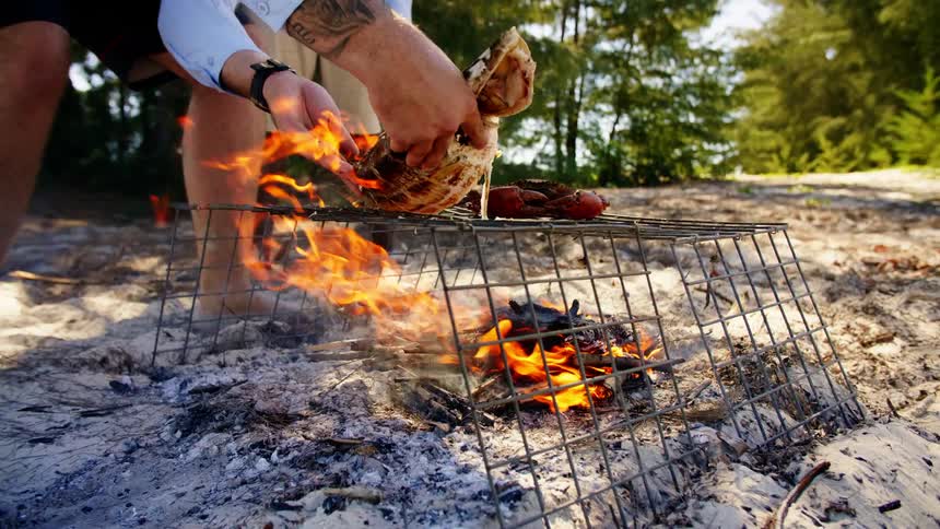 People cooking fish and crab over a fire over the sand in a tropical beach