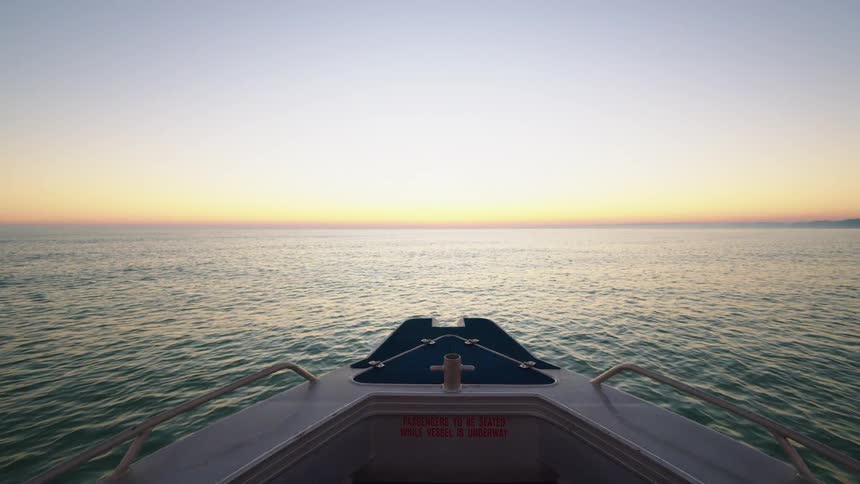 A boat travels across the open ocean under a clear sky