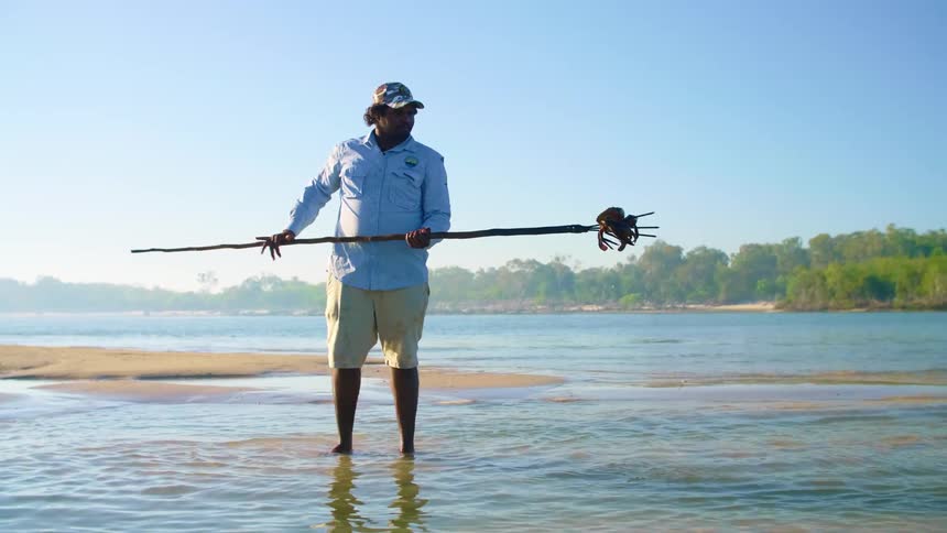 A man uses a long spear to stab crab in a lake