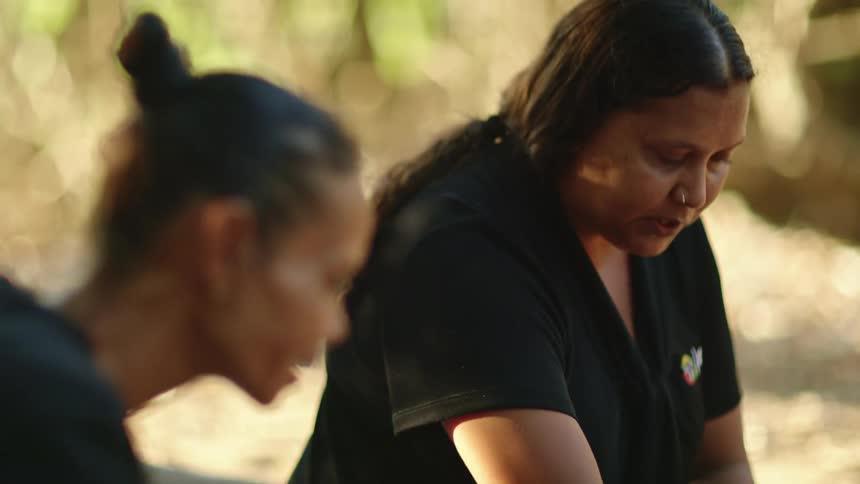 Two people examine some spices and food at a picnic