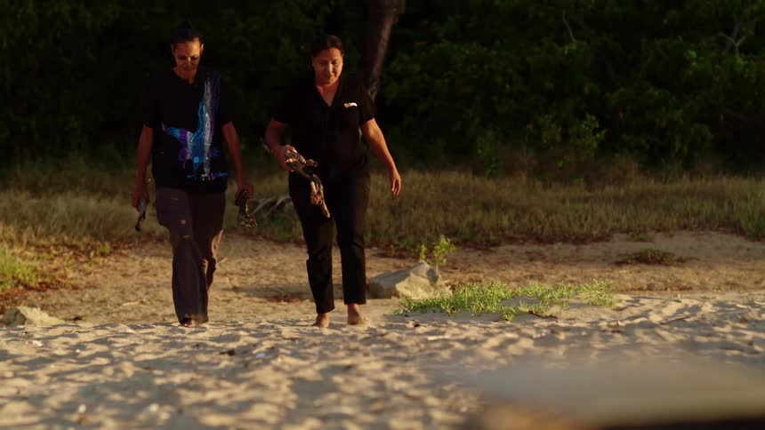Two women walking in the sand on a beach