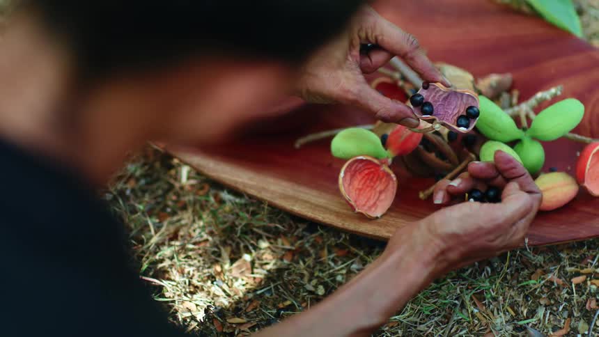 Person removing inside of fruit on wooden tray