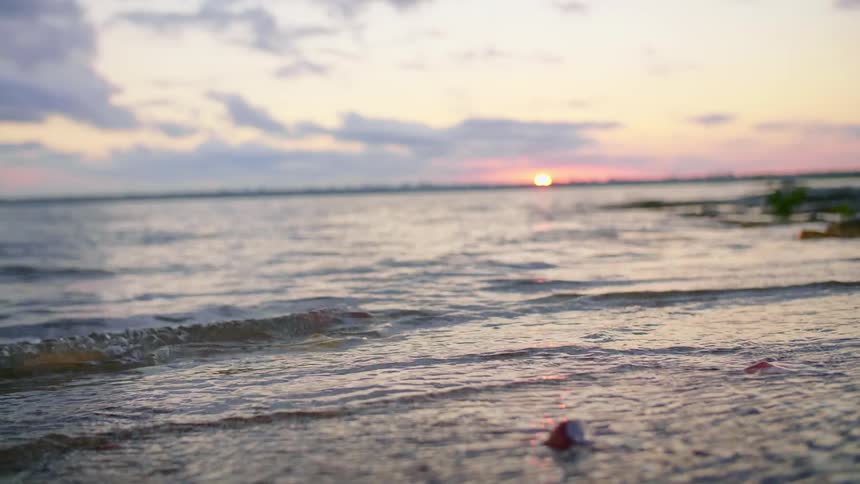 Small ripples in water on beach at sunset