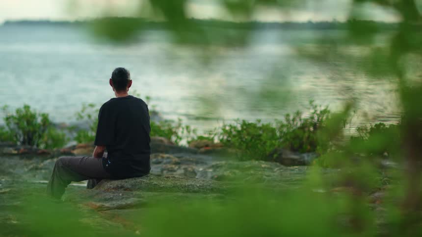An aboriginal woman sitting on a log next to a river