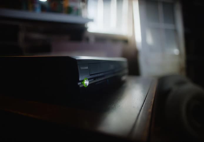 A person presses the power button on a vhs player