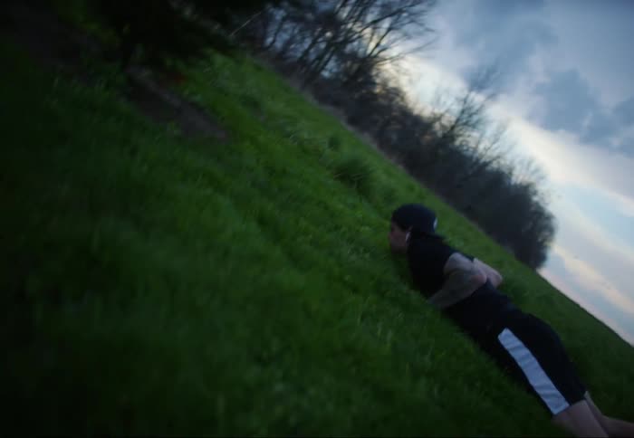 A person falls to the rural ground in a push up position and then jumps back up quickly