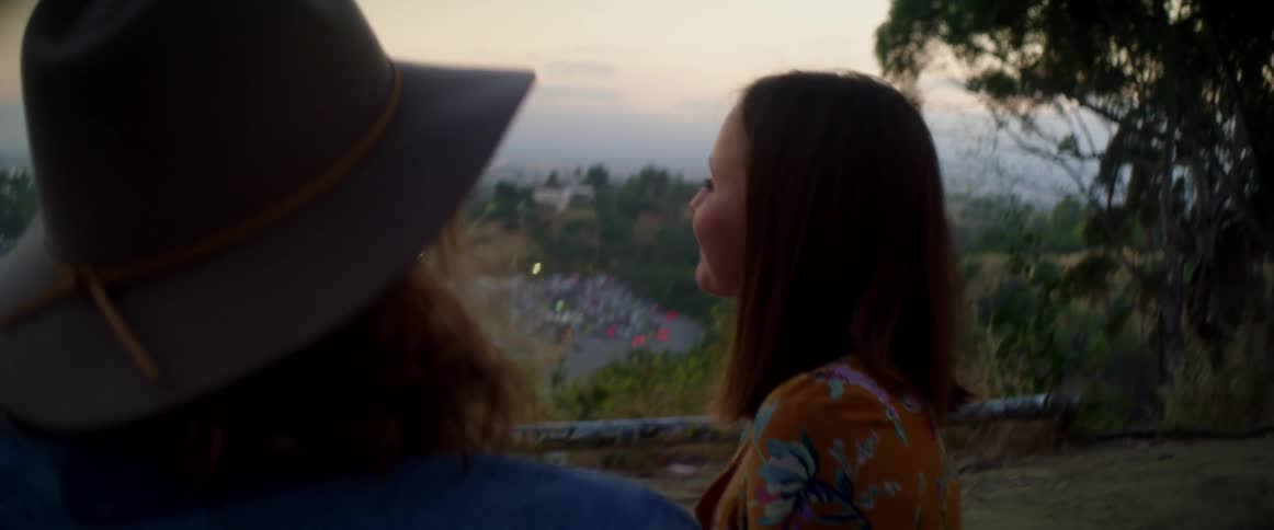 Friends stand on hill looking out toward view that includes a fog covered skyline