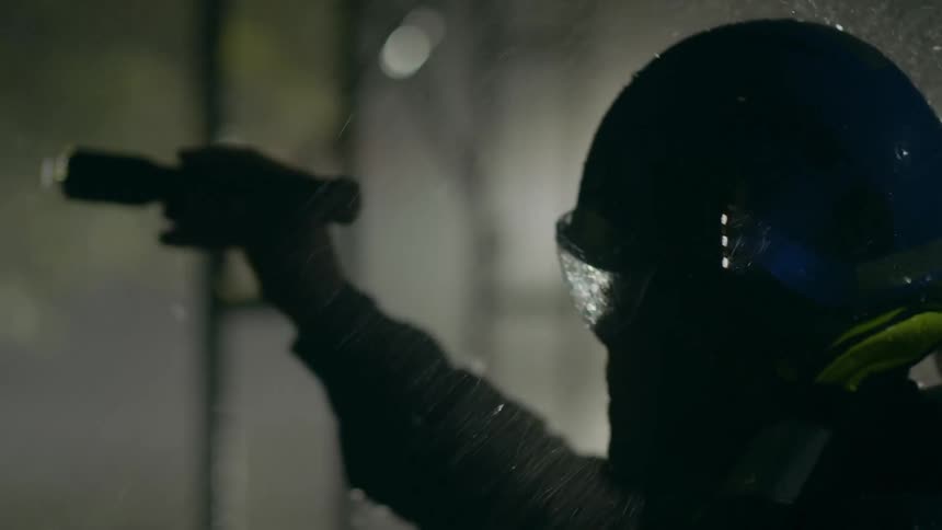 A man standing in water during a rainstorm holds a flashlight as he looks for someone