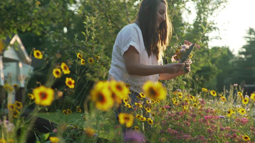A teenage girl at home cuts flowers outside