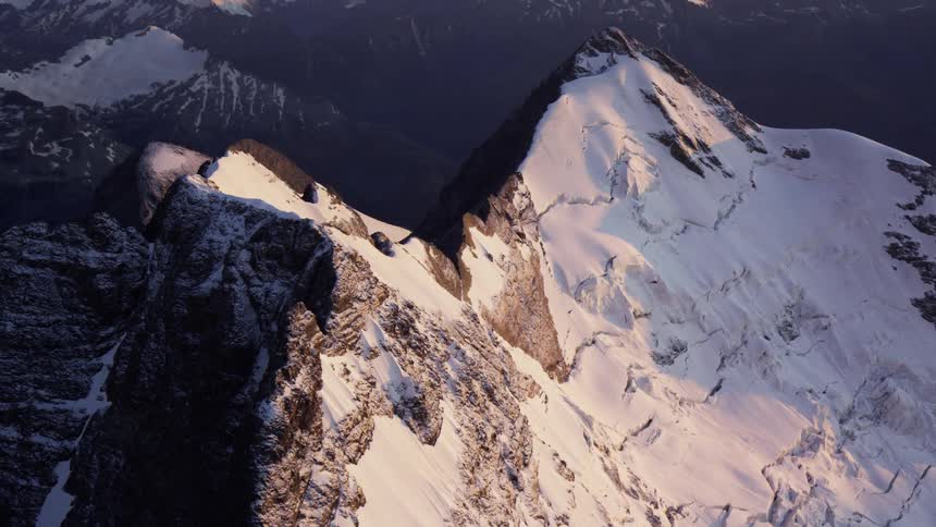 A snow capped mountain ridge in the evening