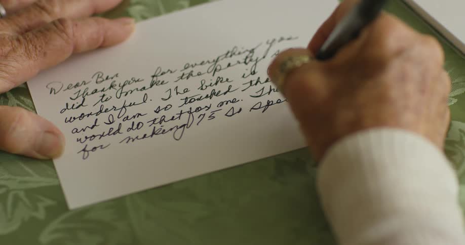 Elderly woman writes a letter with a pen