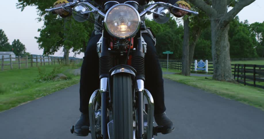 A biker rides a motorcycle down a narrow country road