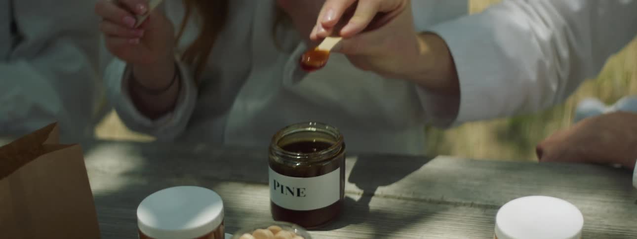 A man nods his head in approval after sampling a jar of honey labeled as pine
