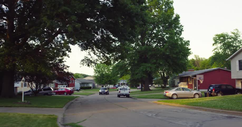 A lone car drives on the neighborhood road