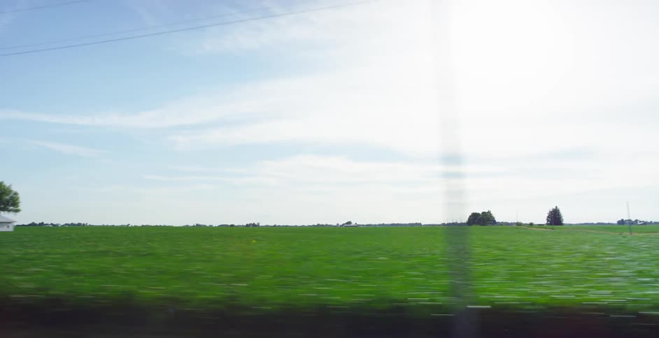 A farm with several buildings is positioned in the midst of sprawling fields of crops